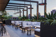 Modern outdoor patio with seating area, plants, and urban skyline.